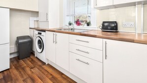 A modern kitchen with white cabinetry, a wooden countertop, a washing machine, and a toaster. - One Bedroom Apartment by Klass Living Serviced Accommodation Hamilton - Back'O'Barns Apartment With WiFi (Hamilton)