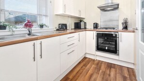 A modern kitchen with white cabinets, a wooden countertop, a built-in oven, and a window with plants. - One Bedroom Apartment by Klass Living Serviced Accommodation Hamilton - Back'O'Barns Apartment With WiFi (Hamilton)
