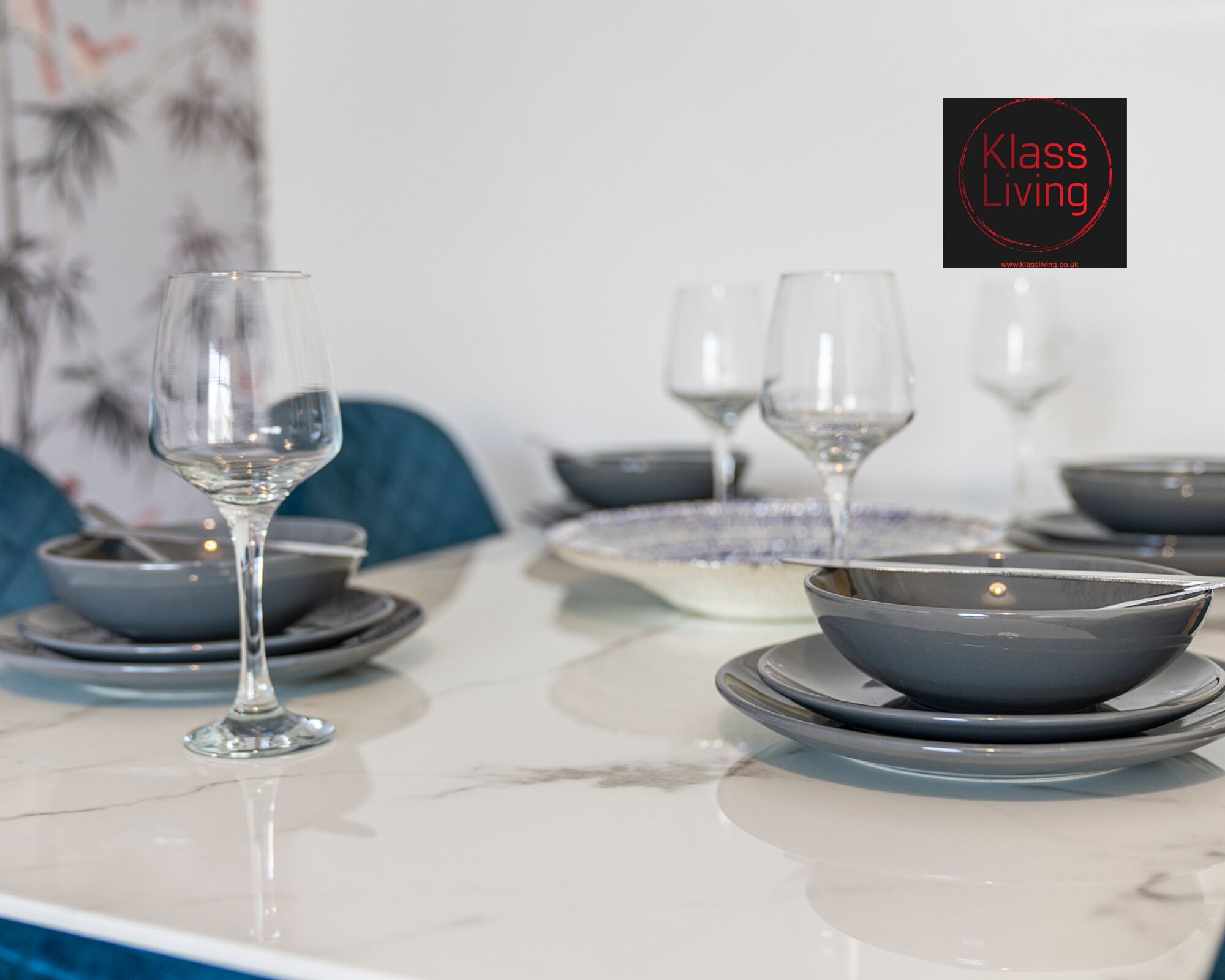 Uma mesa de jantar posta com pratos, tigelas e copos de vinho.
