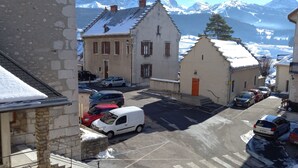 Una vista di una strada con edifici, auto parcheggiate e una montagna innevata sullo sfondo.