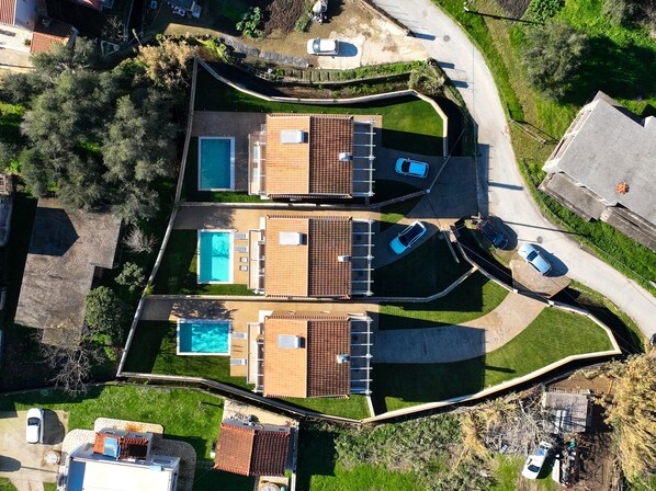 Vue aérienne d’une propriété résidentielle comprenant deux bâtiments distincts, chacun doté d’une piscine, d’un patio couvert et d’un espace de stationnement.