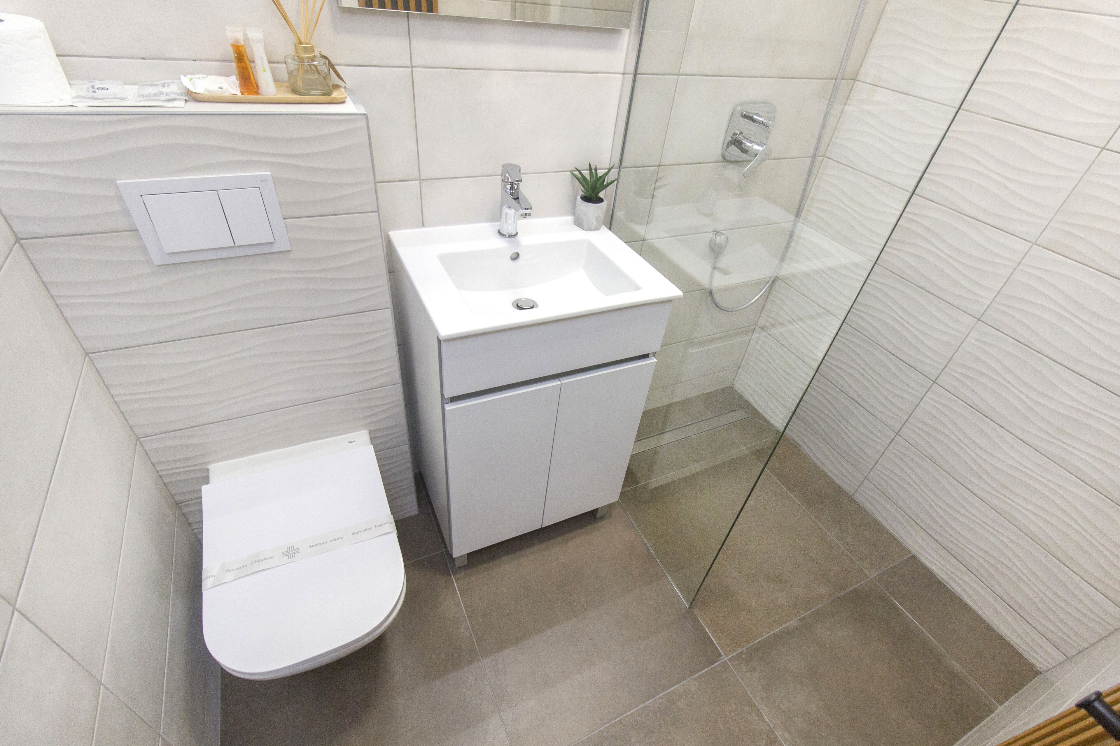 A modern bathroom with a white sink, toilet, and shower.