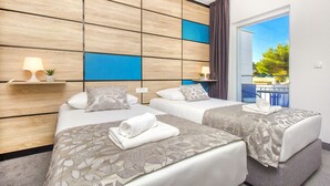 A hotel room with two beds, a wooden headboard, a balcony with a view, and a small plant on the nightstand. - Ville Imperial Vodice (Vodice)
