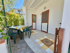 A patio with a table and chairs, a patterned floor, and a door with a shutter.