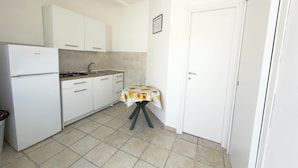 A compact kitchen with white cabinets, a gas stove, and a tiled floor.