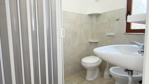 A bathroom with a shower, toilet, and sink.