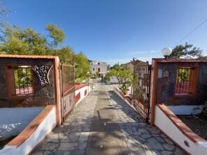 A stone pathway leading to a white building with a red roof, surrounded by greenery and metal gates. - Villa Maica 6, Palinuro, Cilento (Palinuro)