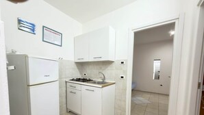 A compact kitchen with white cabinets, a gas stove, and a built-in oven. - Villa Maica 8, Palinuro, Cilento (Palinuro)