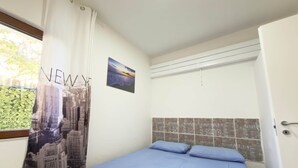 A bedroom with a bed, a window with a curtain, a wall-mounted picture, and a tiled wall. - Villa Maica 8, Palinuro, Cilento (Palinuro)