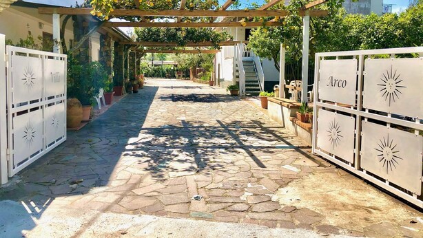 A stone-paved courtyard with a pergola covered in climbing plants, white gates labeled "Villa" and "Arco", and a staircase leading to a building. - Villa Arco 1, Palinuro, Cilento (Palinuro)