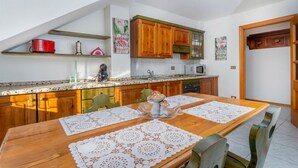 A kitchen with wooden cabinets, a microwave, and a dining table with lace tablecloths.