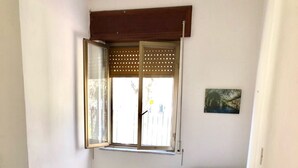A small, clean room with two single beds, a window with a wooden blind, and a small painting on the wall. - Villa Arco 5, Palinuro, Cilento (Palinuro)