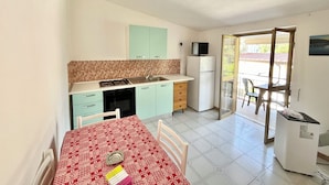 A compact kitchen with a dining area, a refrigerator, and a television on a counter. - Villa Arco 7, Palinuro, Cilento (Palinuro)