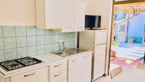 A compact kitchen with white cabinets, a gas stove, a sink, and a small refrigerator. - Villa Arco 2, Palinuro, Cilento (Palinuro)