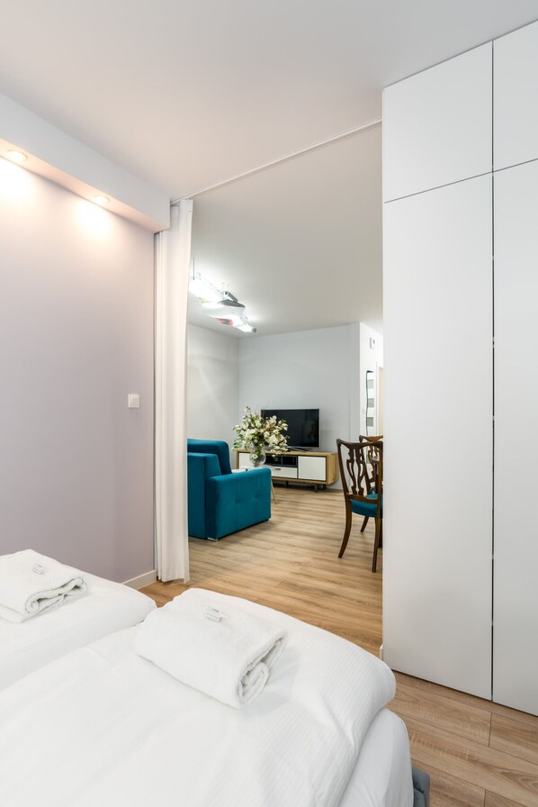 Habitación de hotel con dos camas, televisión, sofá y una mesa de comedor.