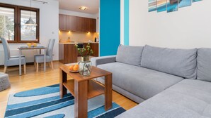 Ein modernes Wohnzimmer mit einem grauen Sofa, einem Holztisch und einem Essbereich inklusive Tisch und Stühlen.