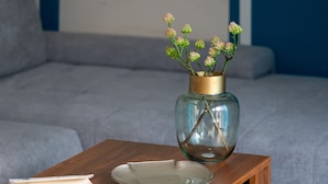 Ein Zimmer mit freiem Blick, einem Holfnachtisch, einer Blumenvase und einem Buch.