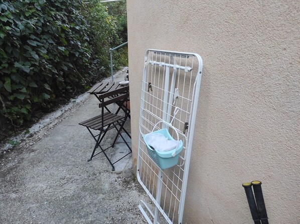 A gated area with a metal gate, a concrete path, a wooden bench, and a table with chairs. - Small house near Saint-Clair Beach in Le Lavandou (Le Lavandou)