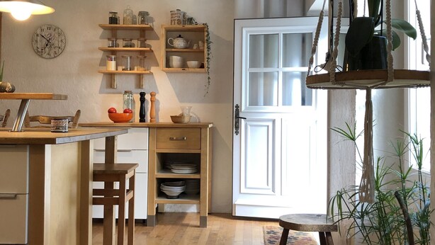 Eine gemütliche Küche mit Holzböden, einem eingebauten Kühlschrank, einem Holzessttisch und einer hängenden Orchideenpflanze.