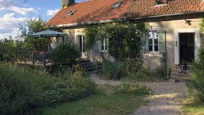 Ein Haus mit Ziegeldach, überdachter Veranda und Garten.