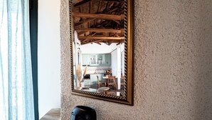 Espelho com moldura de madeira refletindo uma área de cozinha com armários e uma cadeira.