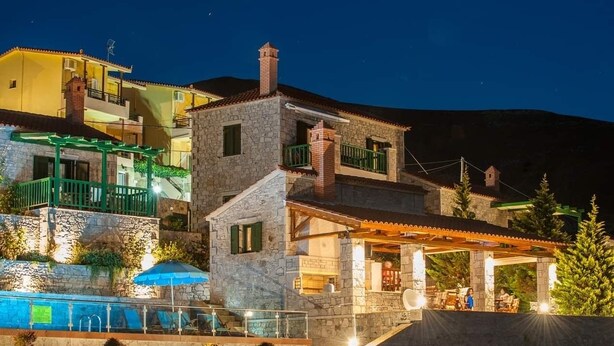 Uma villa de pedra com piscina, área de estar externa e um alpendre coberto.