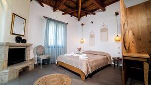 Quarto com cama, poltrona, lareira e luminária suspensa.