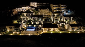 Um edifício de pedra bem iluminado, com várias andares, varandas, piscina e áreas de estar ao ar livre.