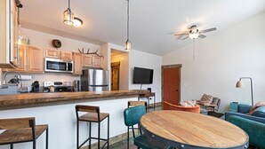 A modern kitchen with wooden cabinets, stainless steel appliances, and a wooden dining table with chairs. - Rustic Modern Home in East Missoula (Missoula)
