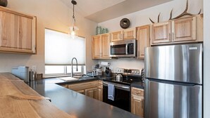 A modern kitchen with wooden cabinets, stainless steel appliances, and a large island. - Rustic Modern Home in East Missoula (Missoula)
