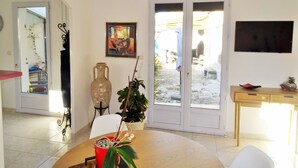 A living room with a dining table, a large vase, a potted plant, and a painting on the wall. - My Guitoune (ST REMY DE PROVENCE)