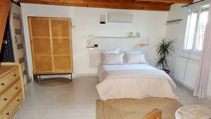 A bedroom with a bed, a wooden wardrobe, a round table, and a potted plant. - My Guitoune (ST REMY DE PROVENCE)
