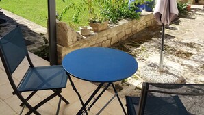 An outdoor patio area with a round table and two chairs, a covered seating area, and a garden with various plants and trees. - My Guitoune (ST REMY DE PROVENCE)