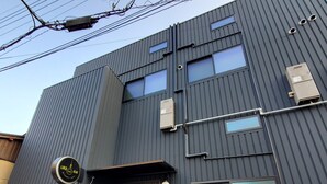 A modern building with a dark facade, multiple windows, and a visible door.
