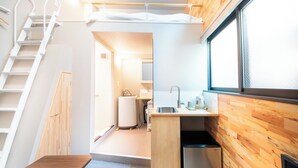A compact room with a bunk bed, a small kitchenette, a sink, and a window.