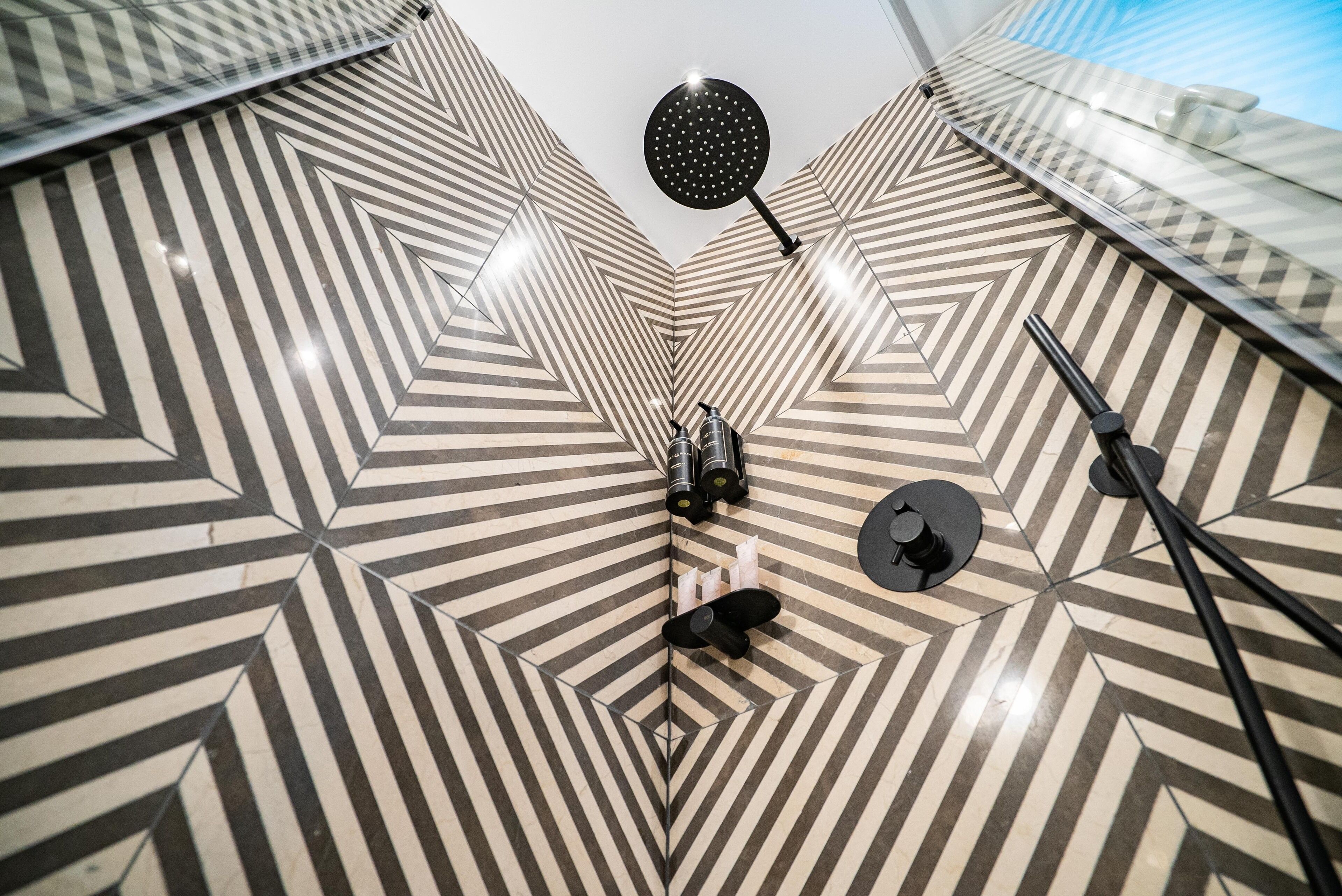 Un interno moderno con pareti a motivi geometrici e un soffitto con un lampadario circolare.