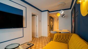 Una sala de estar moderna con un televisor de pantalla plana grande, un sofá amarillo, una mesita y un suelo con diseño.