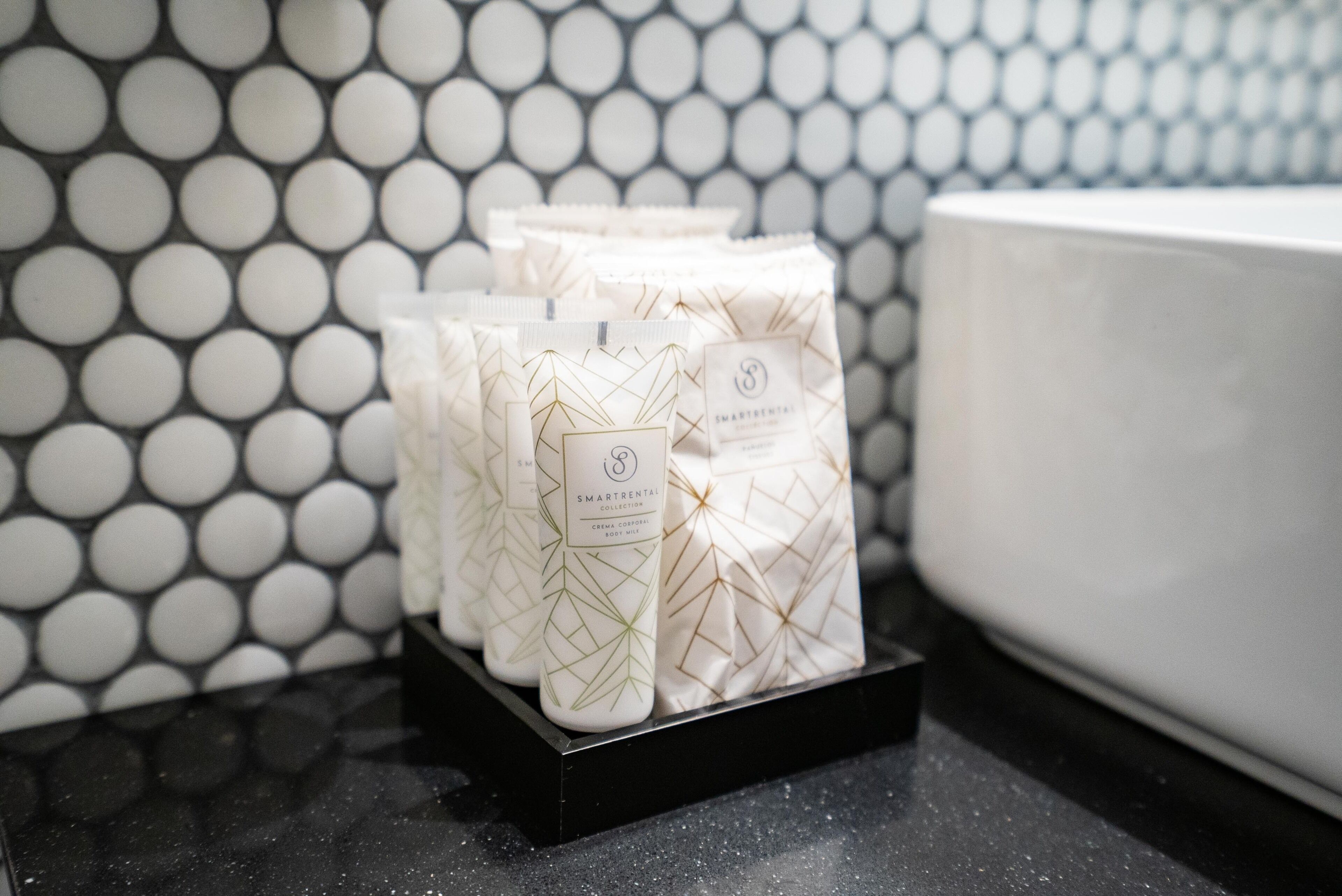 A display of SmartRental collection toiletries on a black tray against a tiled wall.