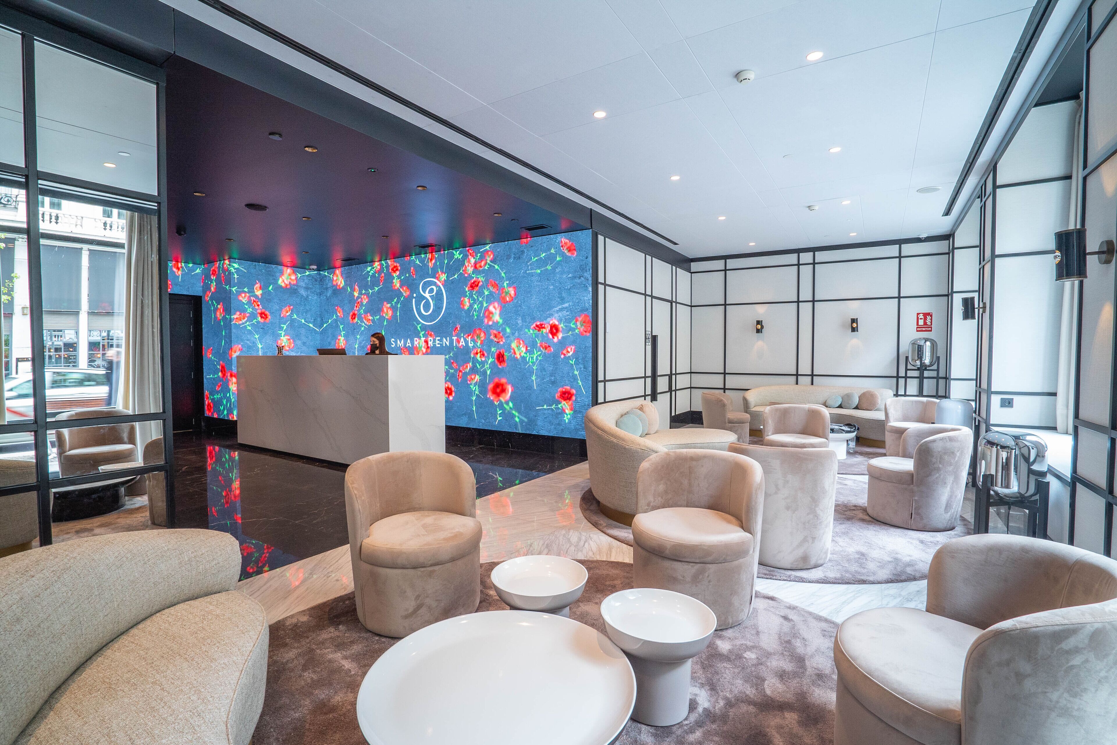 Een moderne lobby met comfortabele zithoeken, een receptiebalie en een grote digitale displaywand.