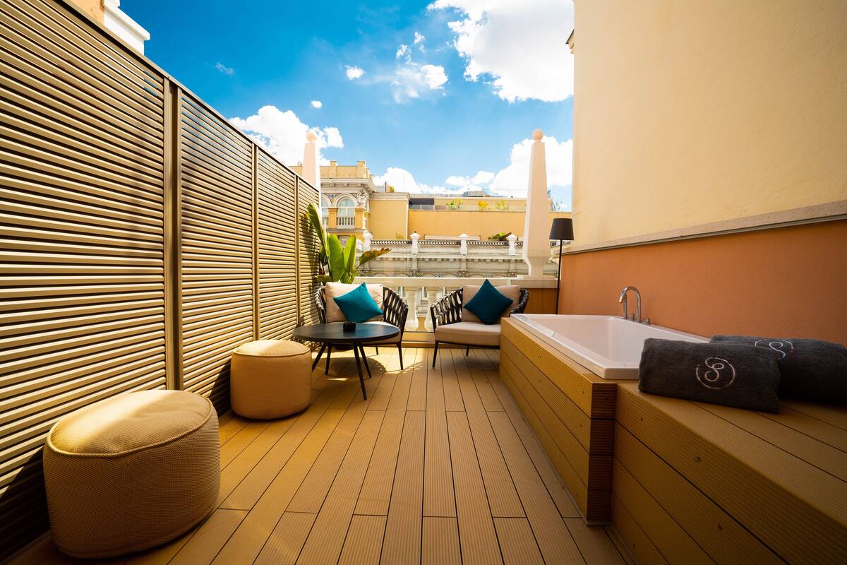 A rooftop terrace with a wooden deck, a hot tub, and outdoor seating.