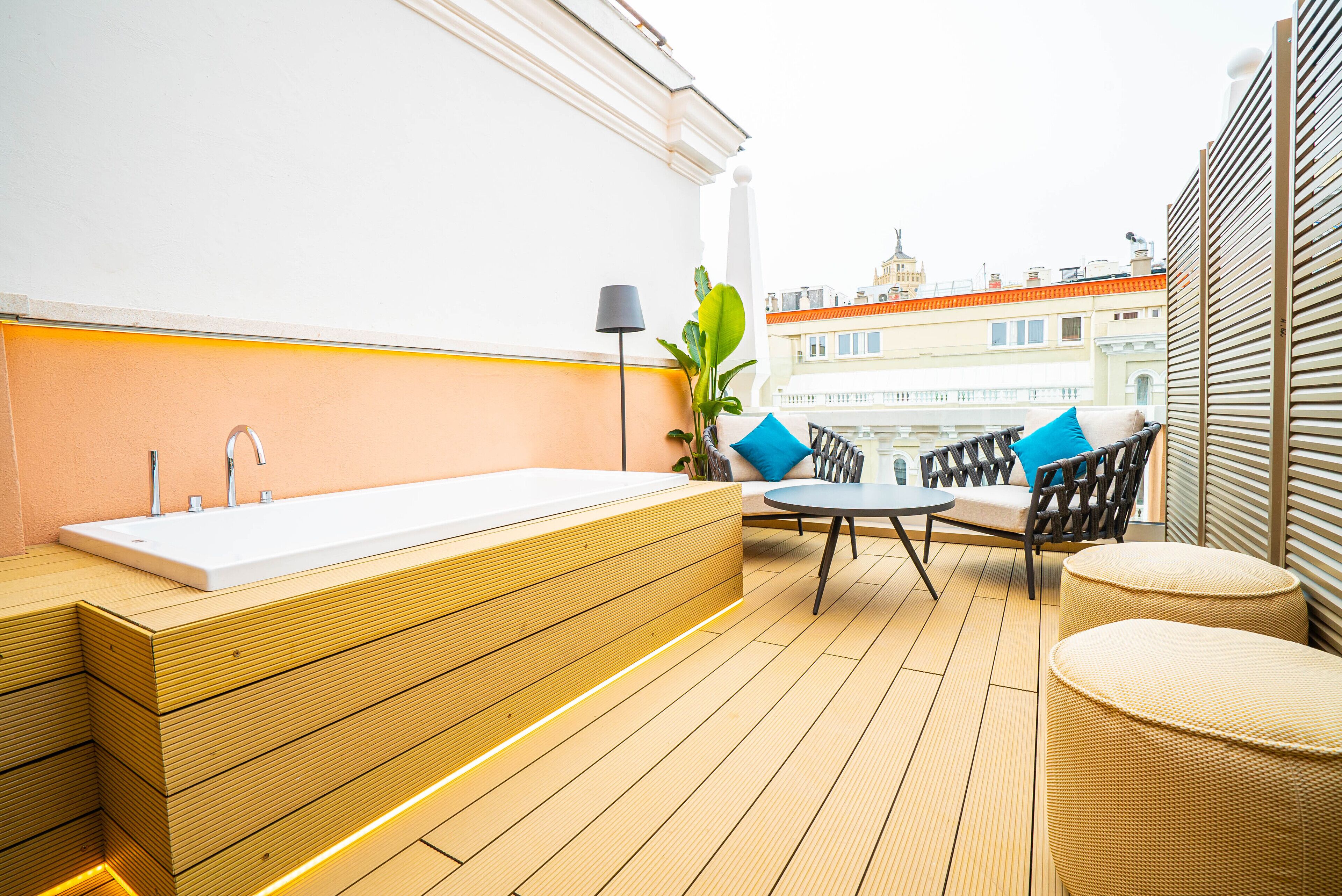 A modern outdoor bathroom with a wooden vanity, a white sink, and a seating area with a table and chairs.