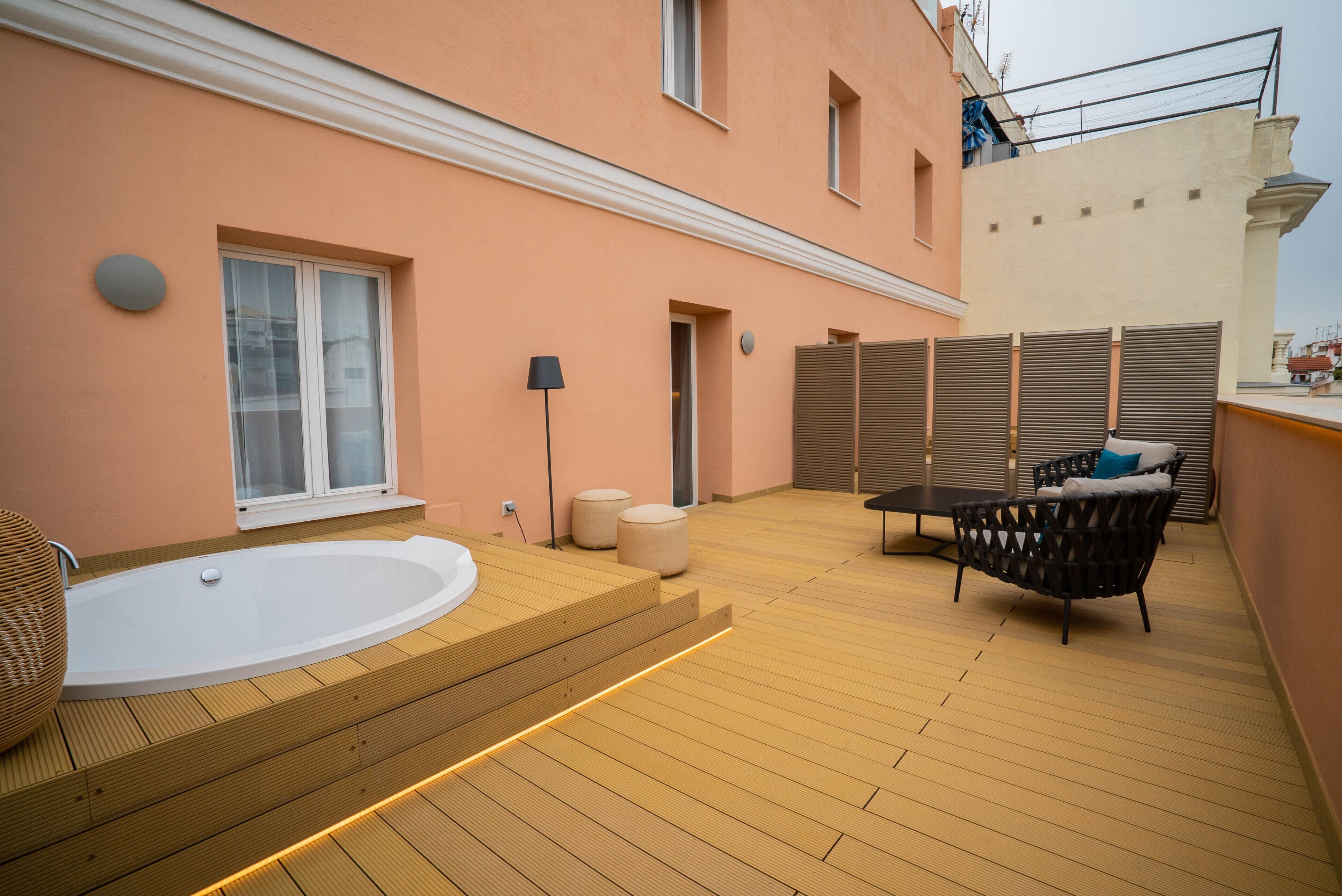 Un área de spa con terraza de madera, un jacuzzi y una zona de estar con cojines.