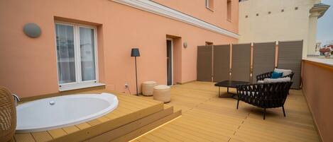 Un área de spa con terraza de madera, un jacuzzi y una zona de estar con cojines.