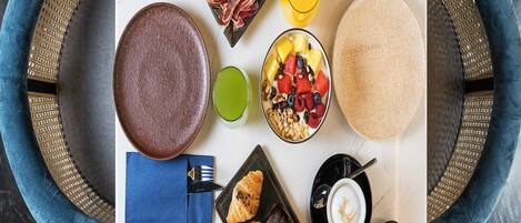 A breakfast tray with bread, meats, fruits, a bowl of yogurt, a croissant, and a coffee cup.