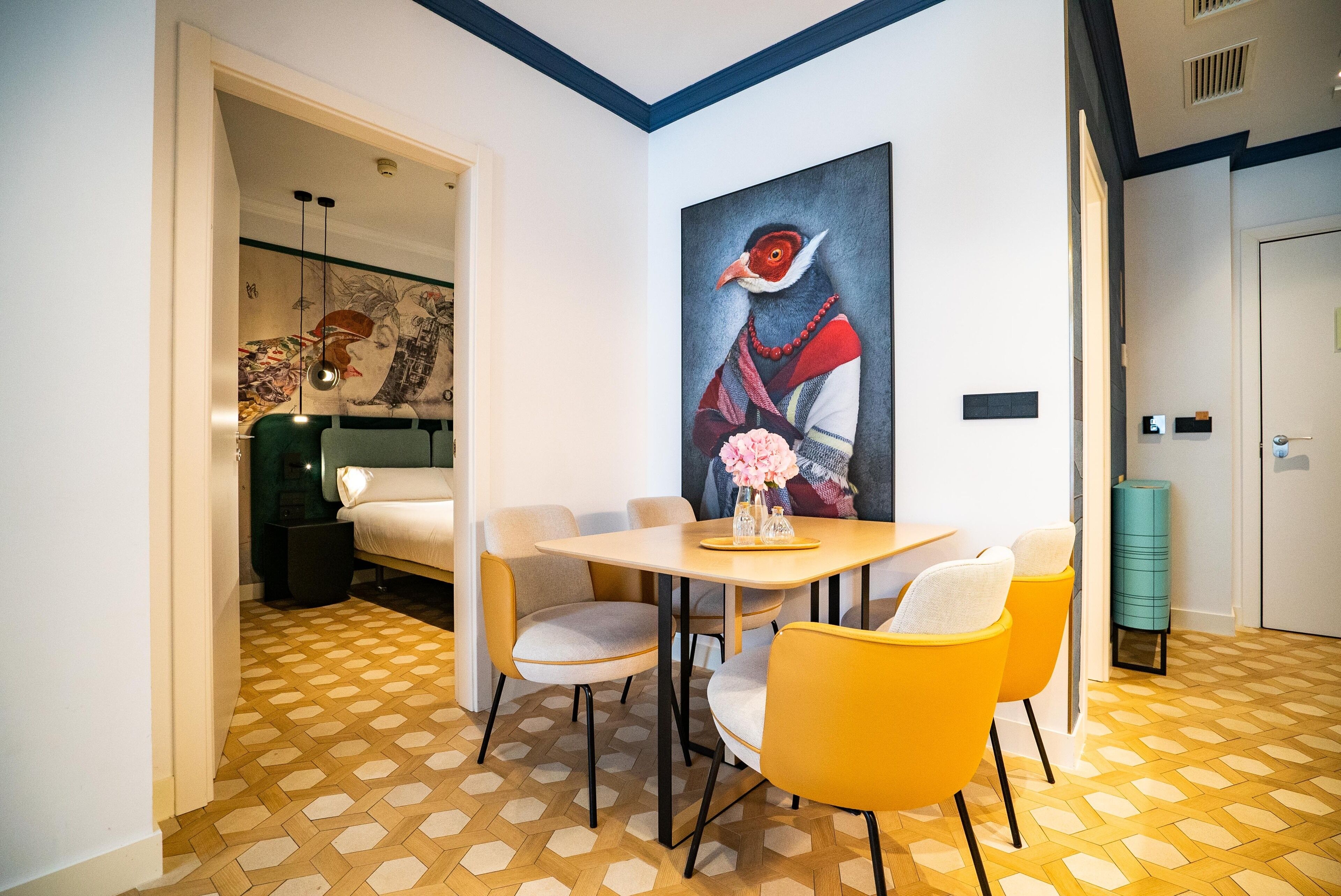 Un comedor con mesa y sillas, un cuadro en la pared y un suelo estampado.