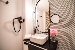 Ein Badezimmer mit einem weißen Waschbecken, einer schwarzen Arbeitsplatte und einem Spiegel an einer Wand mit sechseckigem Muster.