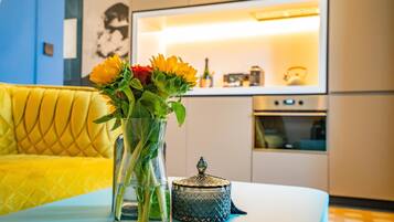 Eine moderne Küche mit Einbauofen und einem Essbereich, ausgestattet mit einem gelben Sofa und einem Tisch mit Blumen.
