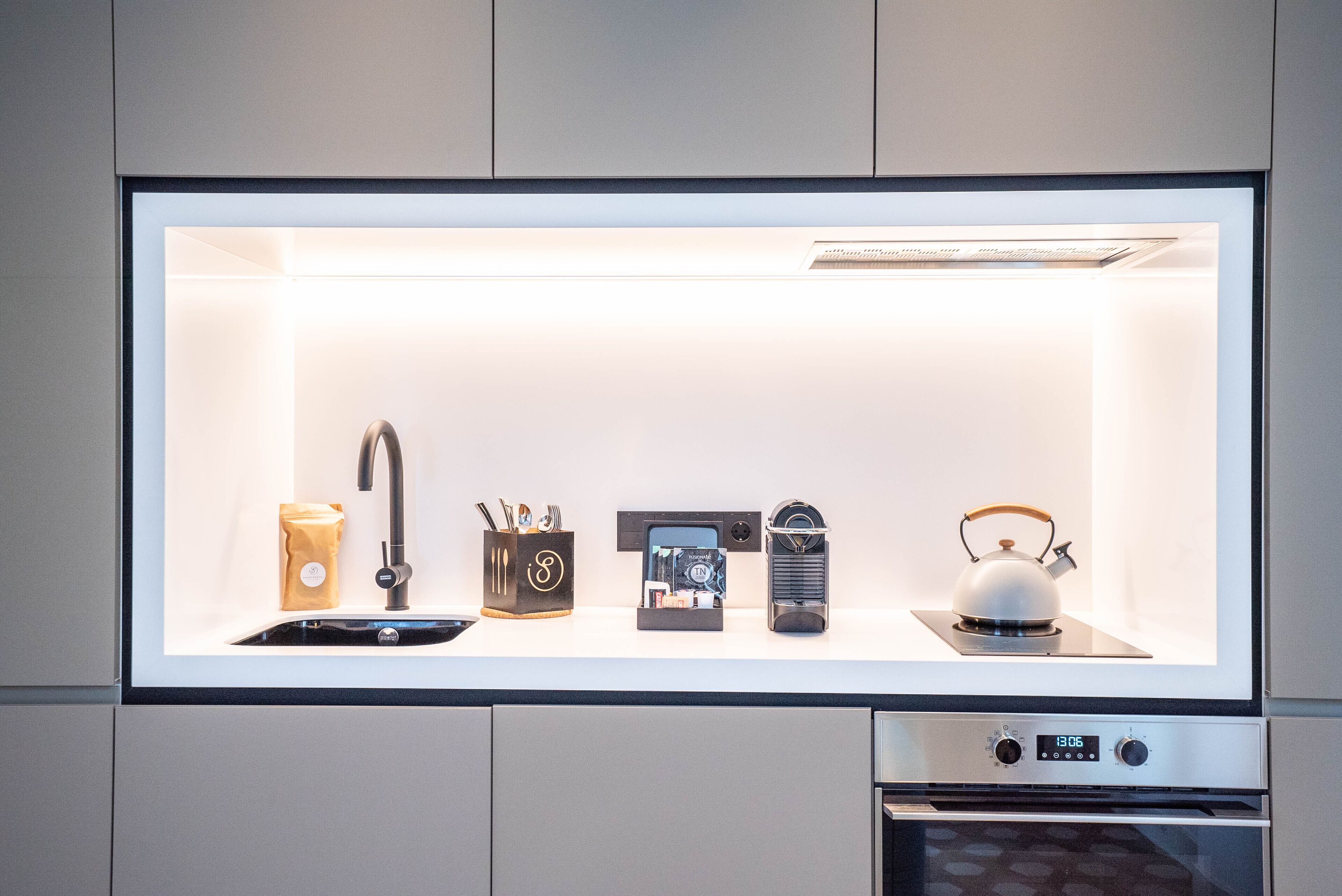 A kitchen with a built-in sink, a kettle, a coffee machine, and a toaster.