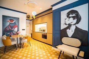 A modern kitchen with a central island, yellow patterned flooring, and a dining area with yellow chairs and a bench.