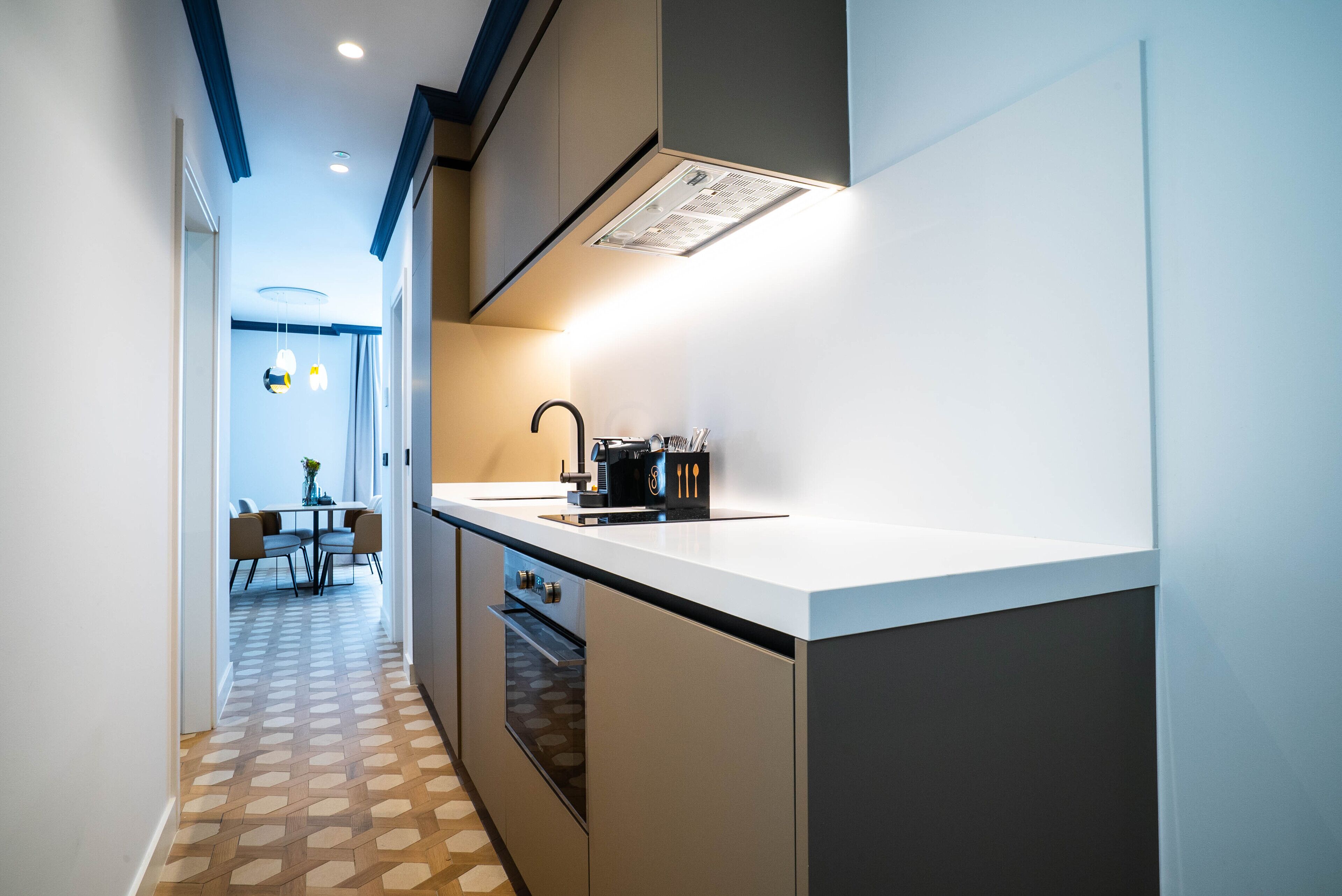 A modern kitchen with a white countertop, a built-in oven, and a black faucet.